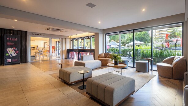 A spacious lobby with modern furniture, large windows, and a view of the outdoor seating area. - Housi Faria Lima (São Paulo)