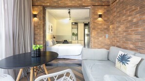A modern room with a brick wall, a bed, a sofa, a dining table, and a small plant. - Housi Faria Lima (São Paulo)