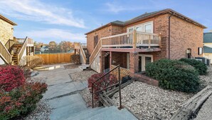 Ein zweigeschossiges Backsteinhhaus mit Balkon, einer Holzterrasse und einem Kiesweg, der zum Eingang führt.