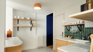 Eine moderne Küche mit weißen Schränken, einer Marmorarbeitsplatte und einem Holzregal.