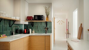 Eine moderne Küche mit Holzschränken, einer weißen Arbeitsplatte und einer grün gefliesten Rückwand.