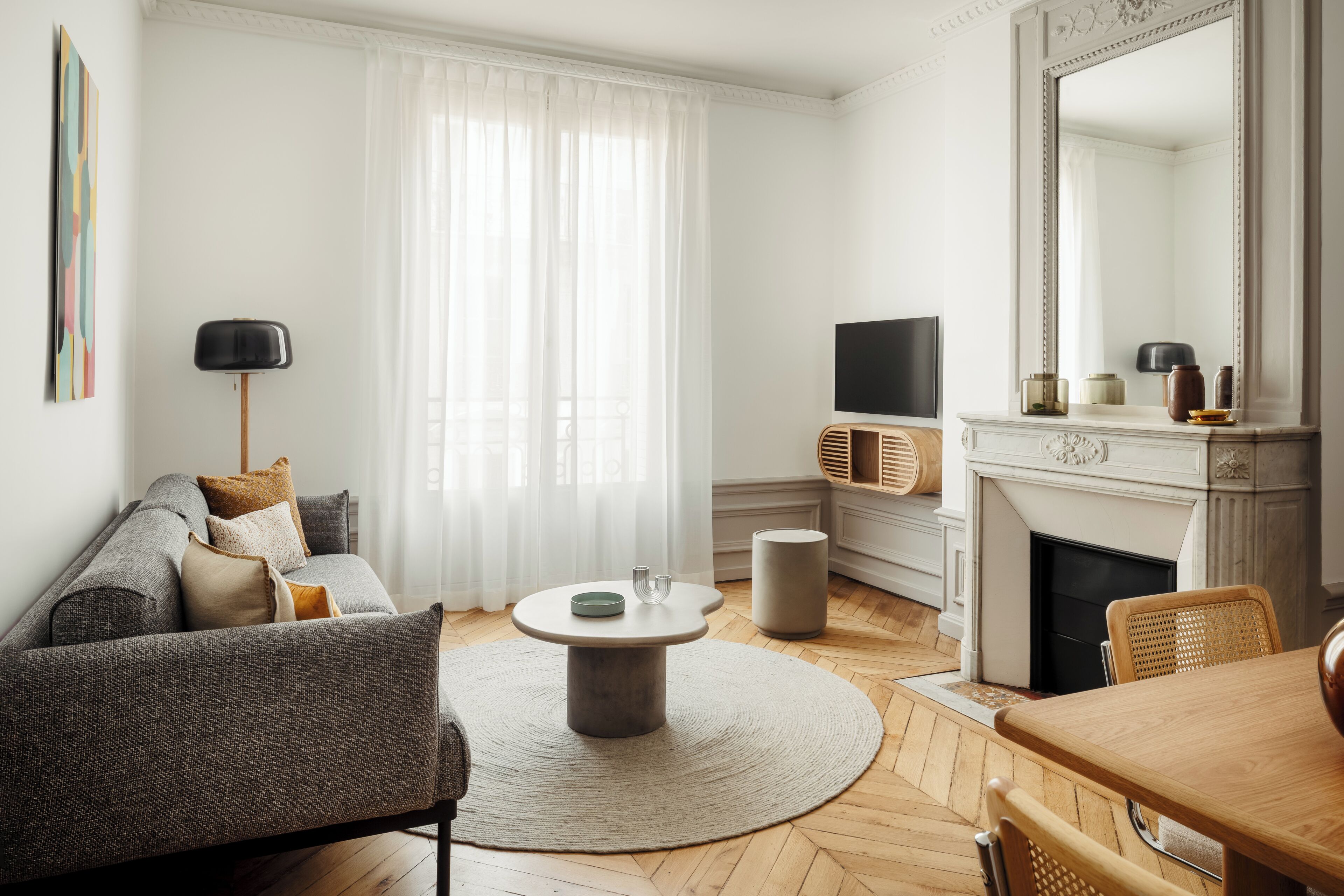 Una sala de estar con sofá, una mesita redonda, chimenea, televisor y un comedor con sillas.