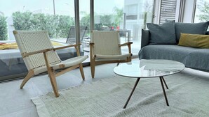 A modern living room with two wicker chairs, a glass coffee table, and a grey sofa with cushions. - TooCoool Villa - Azure Seaview (Paralimni)