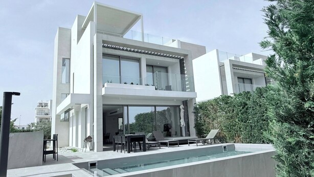 A modern two-story house with a swimming pool, outdoor seating, and a view of the surrounding greenery. - TooCoool Villa - Azure Seaview (Paralimni)