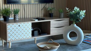 A modern living room with a wooden cabinet, a woven basket, and a vase with green plants.