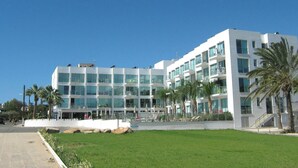 A modern multi-story hotel with a white facade, large windows, and balconies.