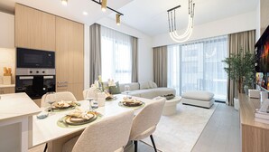Una sala moderna con un sofá, una mesa de comedor con platos y vasos, y una cocina con microondas y horno.