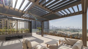 Una terraza moderna en la azotea con un sofá, una mesita y vistas a un horizonte urbano.