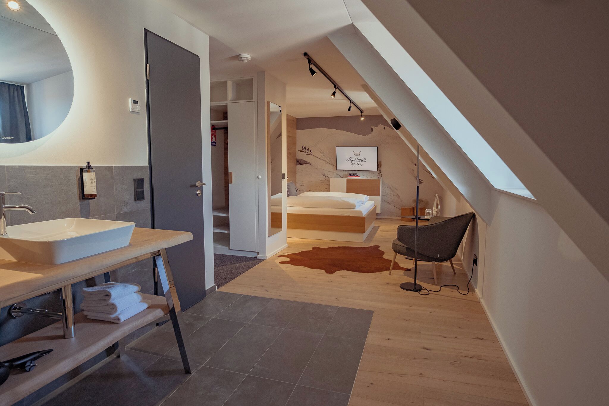 A modern bedroom with a bed, a bedside table, a chair, and a large window.