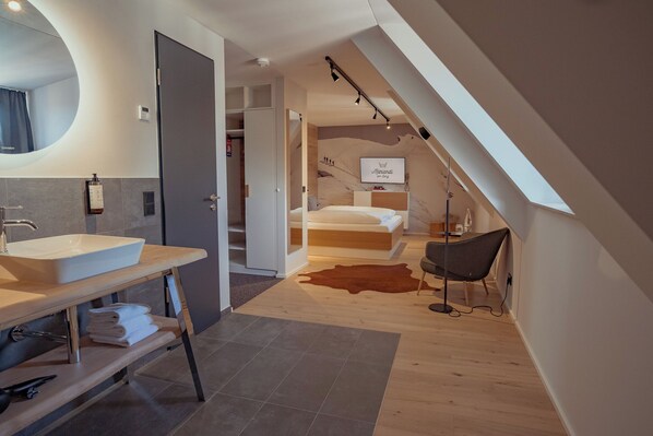 A modern bedroom with a bed, a bedside table, a chair, and a large window. - Mariandl am Berg (Amberg)