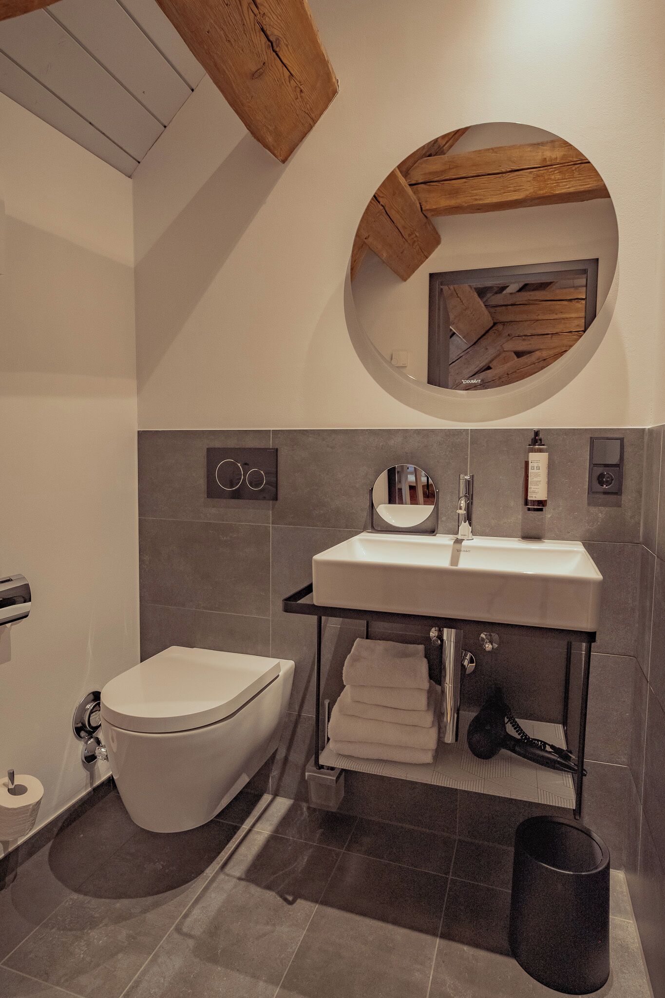 A modern bathroom with a white toilet, a sink with a mirror, and a towel rack.