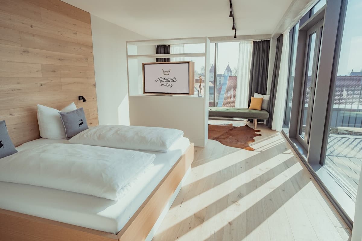 A modern hotel room with a large bed, a seating area with a view, and a framed sign on the wall.