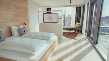 Una habitación de hotel moderna con una cama grande, un espacio de descanso con vistas y un cartel enmarcado en la pared.