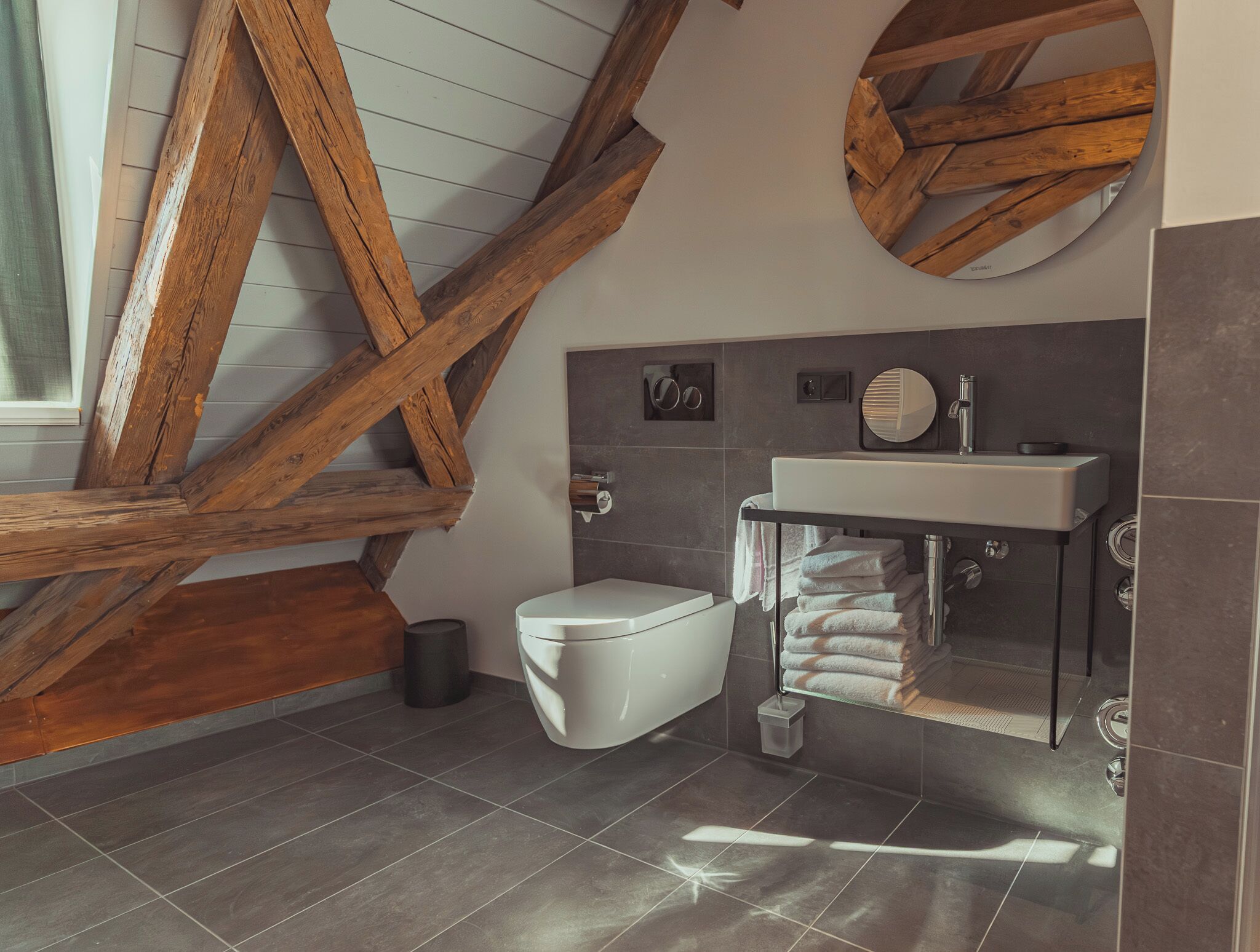 Un baño moderno con un inodoro blanco, un lavabo con espejo y un perchero para toallas.
