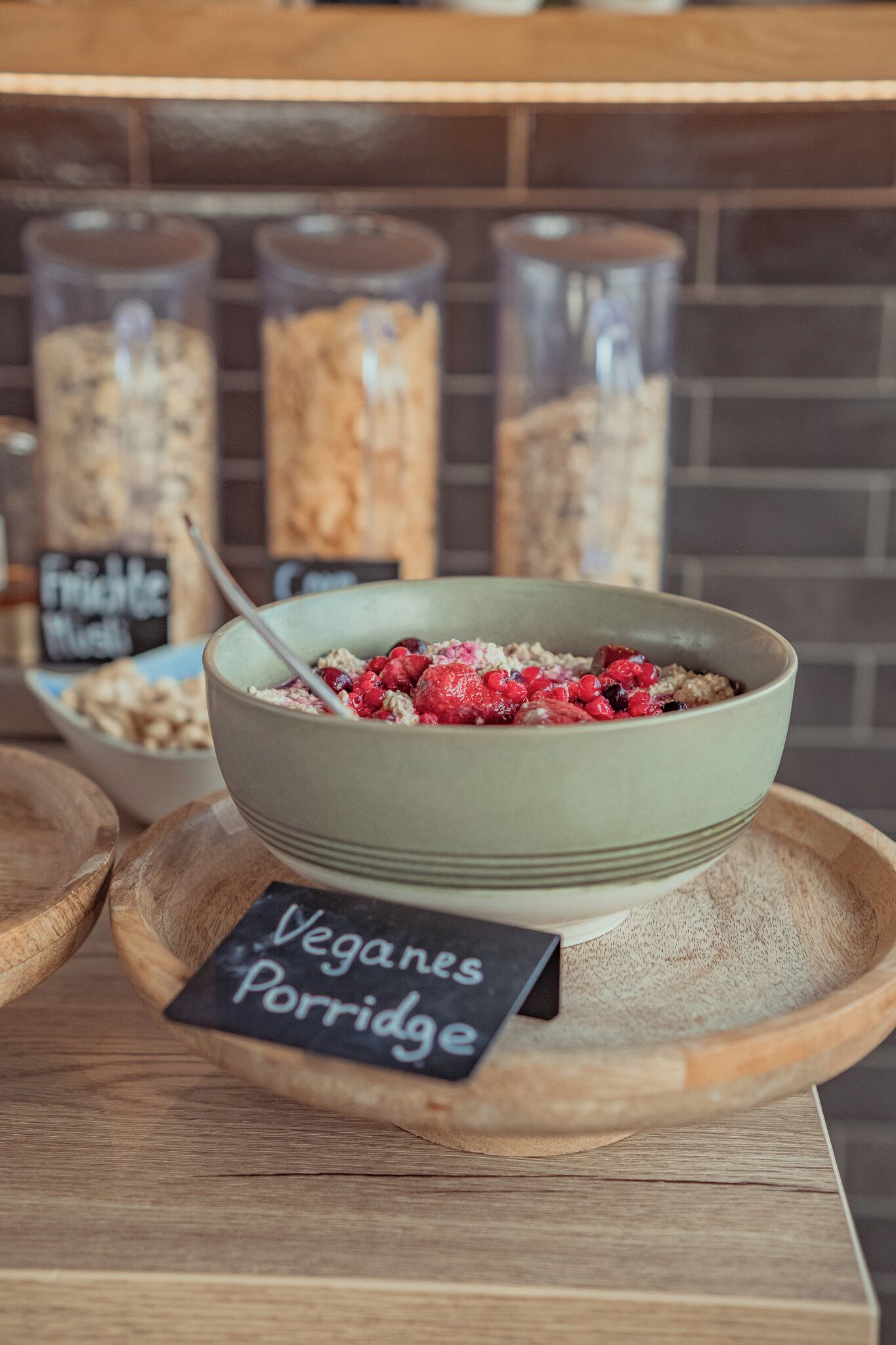 Eine Schüssel veganes Porridge mit Himbeeren auf einem Holztablett, mit einem Schild, das es als vegan kennzeichnet.