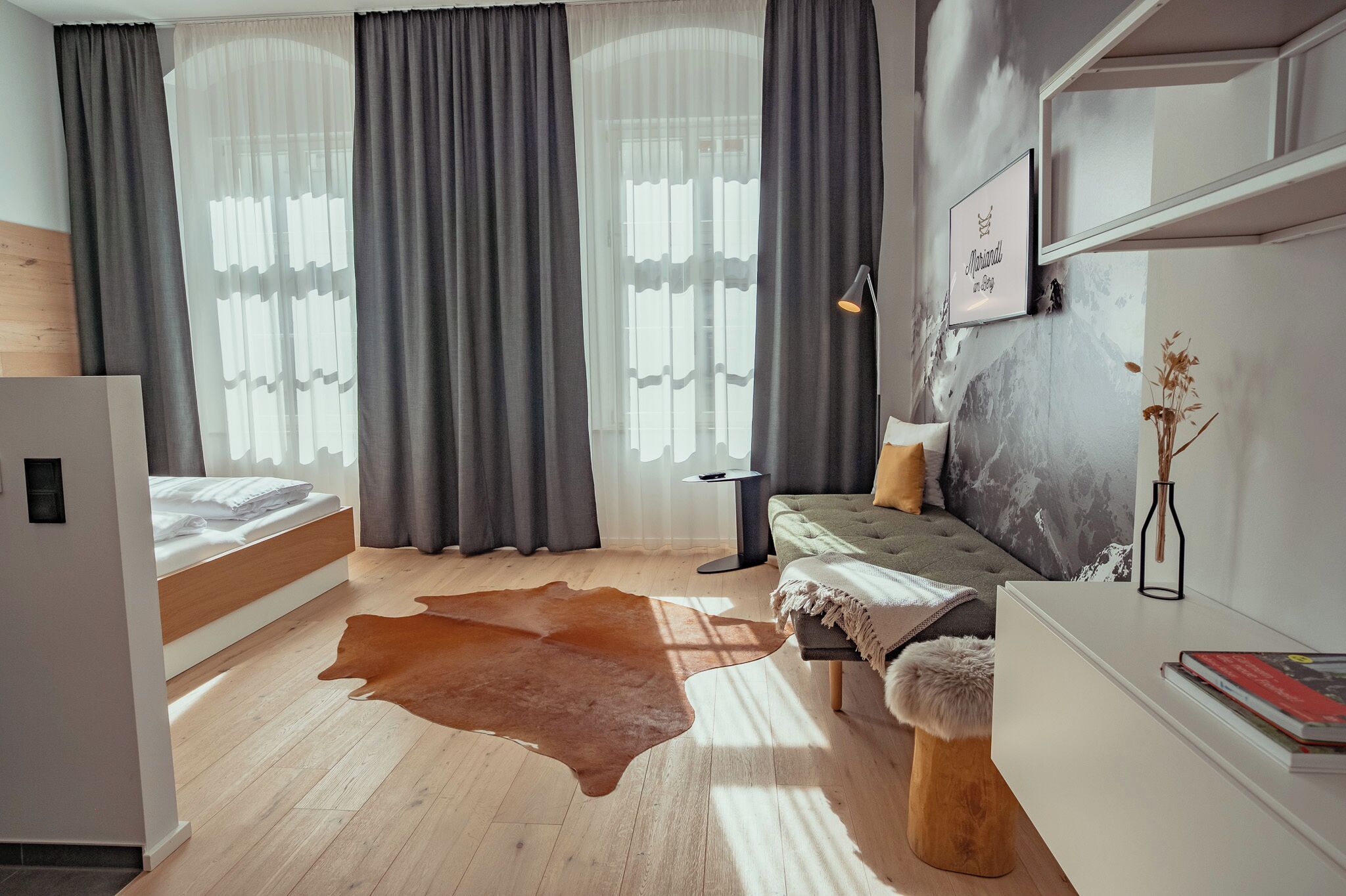 A modern bedroom with a bed, a sofa, a rug, and a desk.