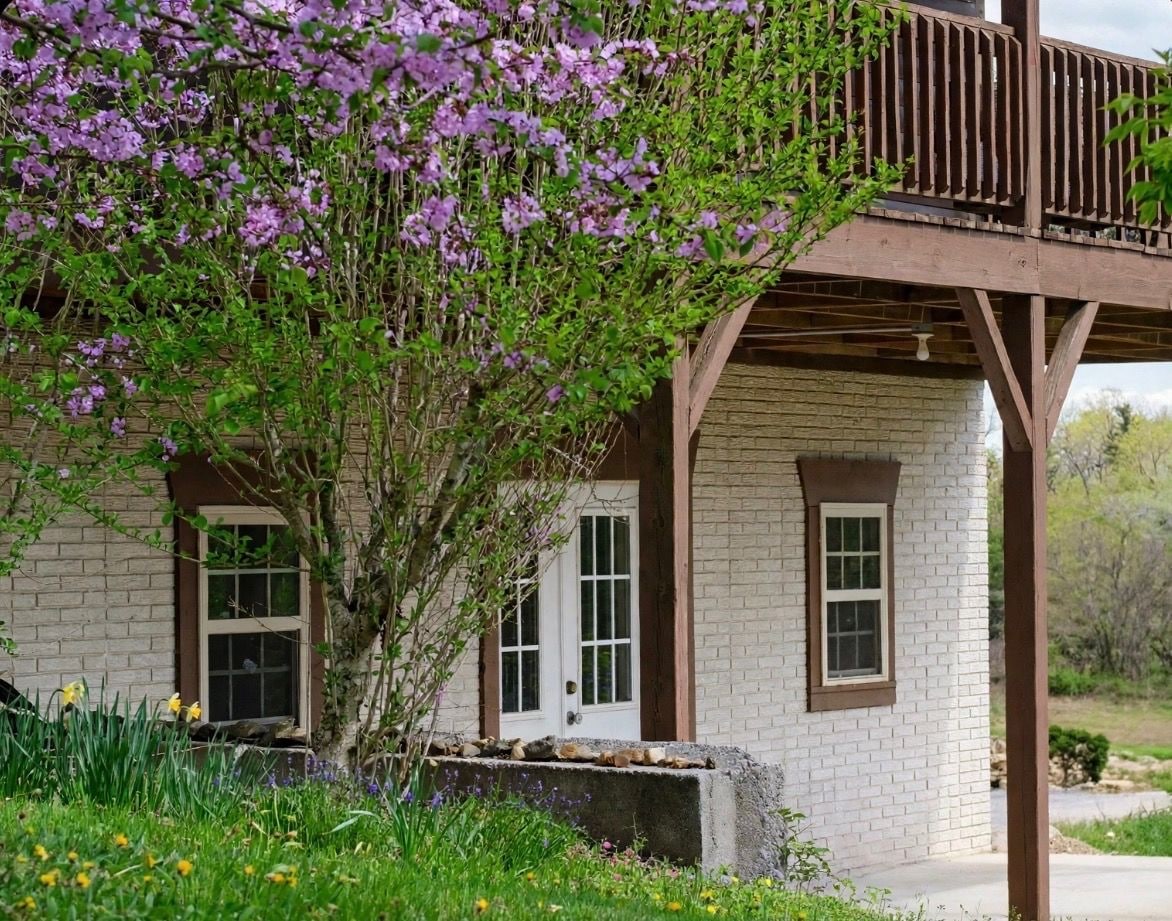 A brick house with a wooden porch, a white door, and a window.