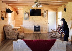 L’intérieur d’une cabane en rondins, avec une cheminée, un téléviseur et des têtes d’animaux empaillées accrochées au mur.