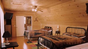 A cozy cabin bedroom with two beds, a ceiling fan, and a wooden interior. - Charming 2-bedroom cabin with AC, WiFi in brilliant Cisco Ga.  (Cisco)