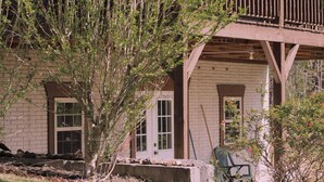 A building with a brick facade, a wooden deck, and a covered porch area. - Charming 2-bedroom cabin with AC, WiFi in brilliant Cisco Ga.  (Cisco)