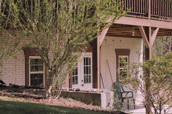 A building with a brick facade, a wooden deck, and a covered porch area. - Charming 2-bedroom cabin with AC, WiFi in brilliant Cisco Ga.  (Cisco)