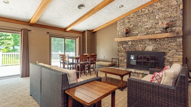 A spacious living area with a stone fireplace, wicker furniture, and a large sliding glass door leading to a balcony.