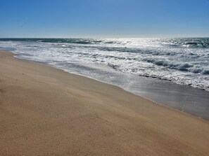Een strand met golven, een heldere lucht en een zandstrand.