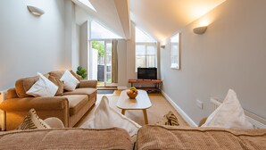 A modern living room with a sofa, a coffee table, and a television.