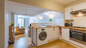 A compact kitchen with a washing machine, a stove, and a sink.