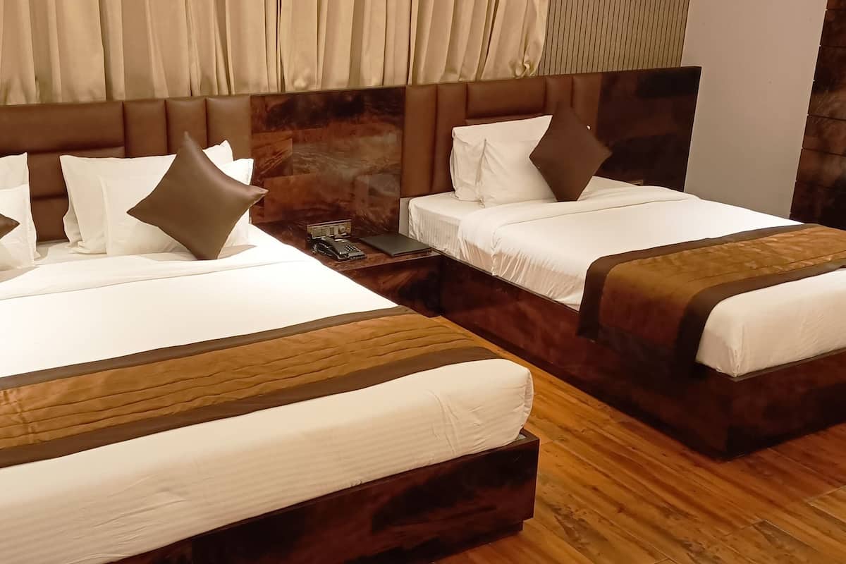 Een hotelkamer met twee bedden, elk voorzien van witte lakens en bruine hoofdeinden.