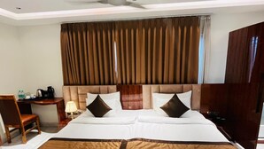 A hotel room with a large bed, a desk with a chair, a lamp, and a wardrobe. - hotel suncity palace (Katihar)