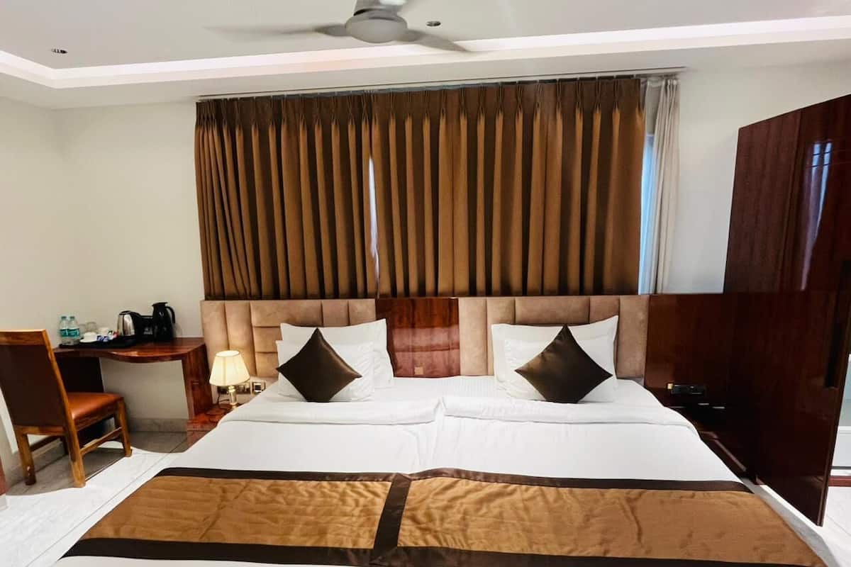 Een hotelkamer met een groot bed, een bureau met stoel, een lamp en een kledingkast.