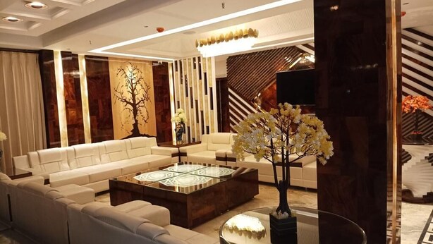 A modern living room with a sofa set, a glass coffee table, and a decorative tree. - hotel suncity palace (Katihar)