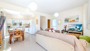 A bright living room with a sofa, TV, and dining area.