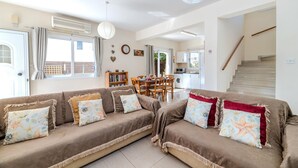 A living room with a sofa set, a dining table, and a staircase.