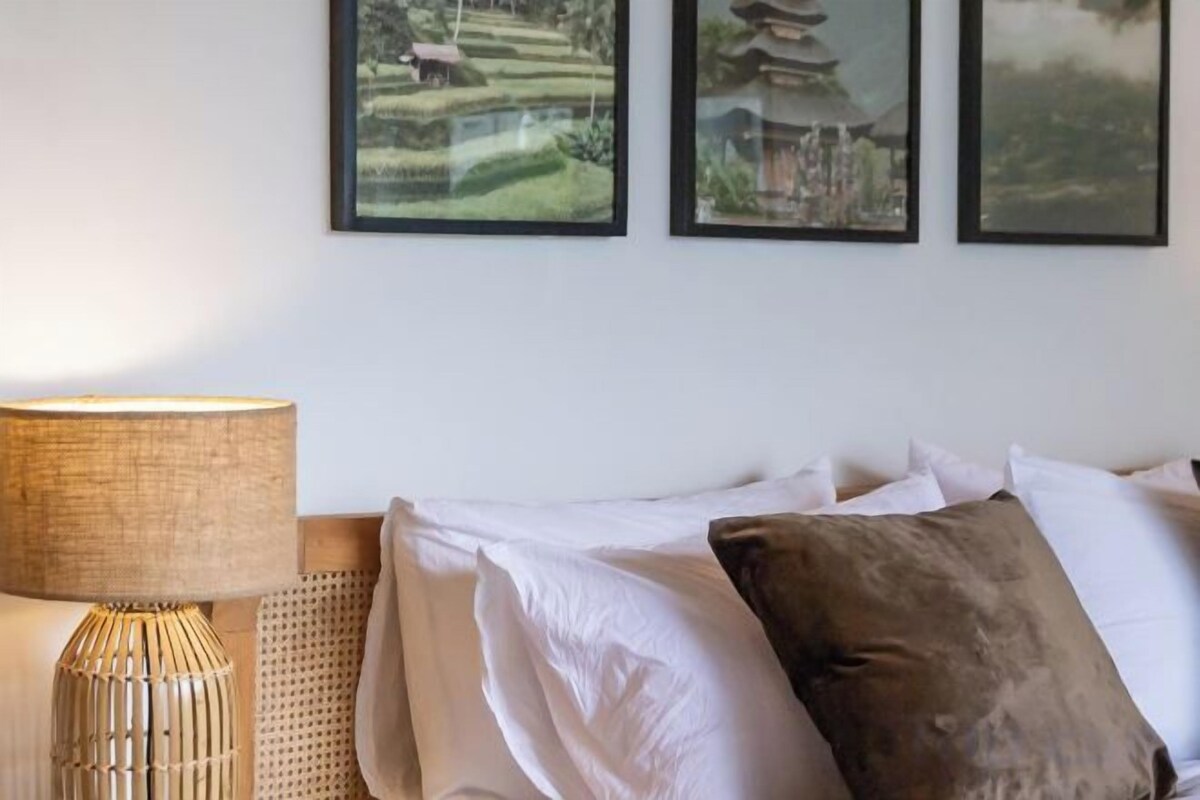 A room with a bed, a lamp, and three framed pictures on the wall.