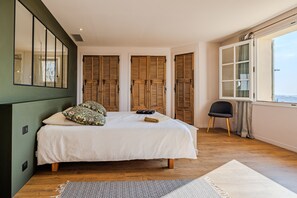 A bedroom with a bed, wooden shutters, a window, and a chair. - Mas Gauda – Garden & family space, Côte d’Azur (La Gaude)
