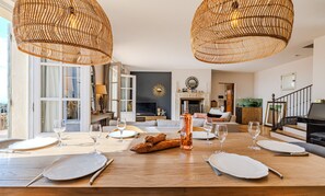 A dining area with a wooden table set for six, surrounded by wicker pendant lights. - Mas Gauda – Garden & family space, Côte d’Azur (La Gaude)