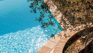 A clear blue pool with a stone border and surrounding vegetation. - Mas Gauda – Garden & family space, Côte d’Azur (La Gaude)