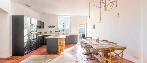 A modern kitchen with a central island, dark cabinets, and a dining area with a wooden table and chairs.