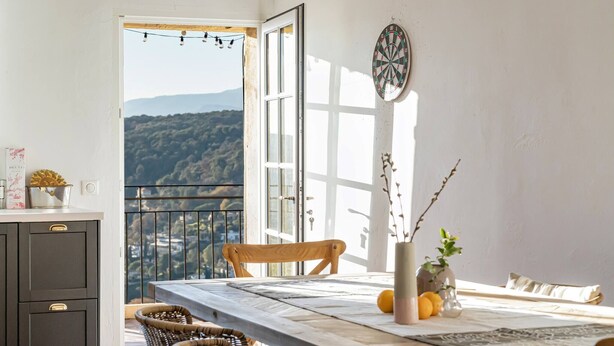 A dining area with a table, chairs, a vase with flowers, and a dartboard. - Apt Chagall – In the heart of Saint-Paul de Vence (Saint Paul de Vence)
