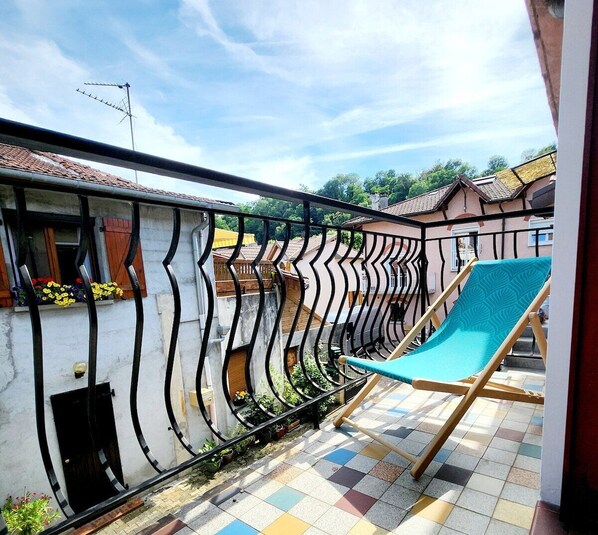 A balcony with a blue chair, a tiled floor, and a metal railing. - Le 56 entre ville&lac sejouraixlesbains (Aix-les-Bains)