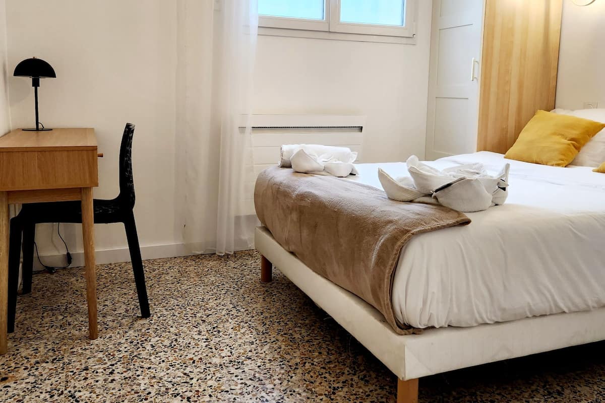 Une chambre d’hôtel avec un lit, un bureau, une chaise et une fenêtre.