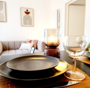 A modern dining area with a candle holder, a glass, and a plate on a table. - Le 56 entre ville&lac sejouraixlesbains (Aix-les-Bains)