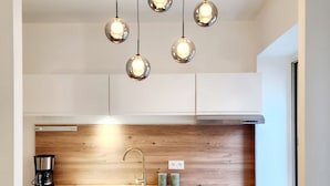 A modern kitchen with a wooden backsplash, a stainless steel sink, and a built-in stove. - Le 56 entre ville&lac sejouraixlesbains (Aix-les-Bains)