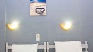 A bedroom with two beds, each with white bedding and a wooden headboard. There are wall-mounted lights on either side of the beds. - La Pensione Skiathos (Skiathos)