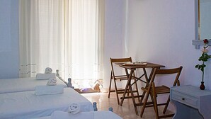 A hotel room with two beds, a desk, and a chair. - La Pensione Skiathos (Skiathos)