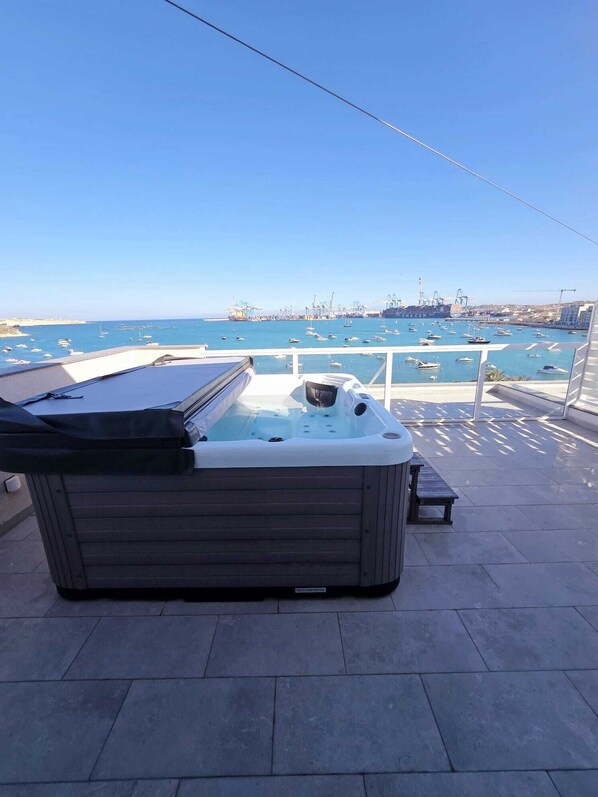 A hot tub on a balcony with a view of a marina and boats. - South32 Hotel (Birzebbuga)