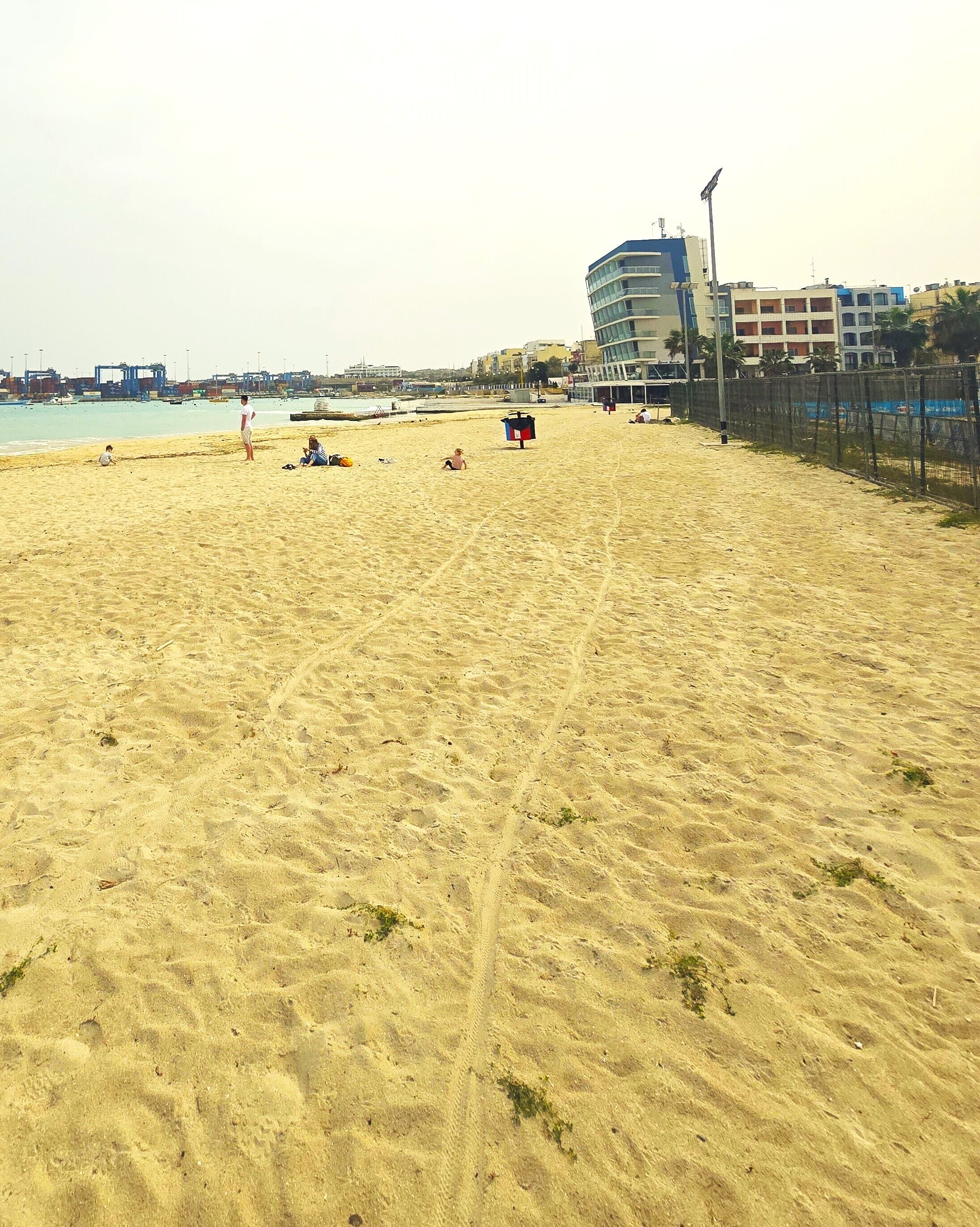 A sandy beach with a few people and a lifeguard tower.