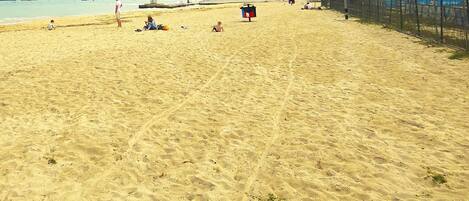 A sandy beach with a few people and a lifeguard tower.